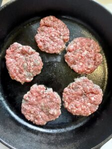 beef breakfast sausage cooking on a cast iron skillet